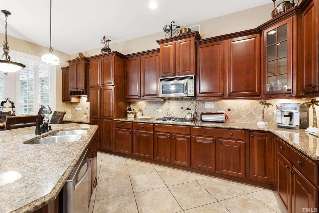 A luxury kitchen featuring tons of natural wood cabinets and tile floor